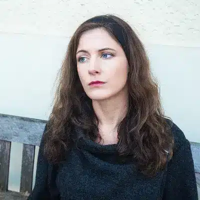 Junge Frau mit dunklen Haaren blickt nachdenklich zur Seite – Akademiker Coaching für internationale Fachkräfte in Deutschland