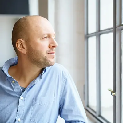 Mann blickt nachdenklich aus dem Fenster – AVGS Coaching Berlin für berufliche Neuorientierung