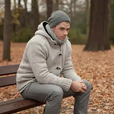 Junger Mann sitzt nachdenklich auf einer Parkbank im Herbst – AVGS Coaching Berlin für Arbeitssuchende