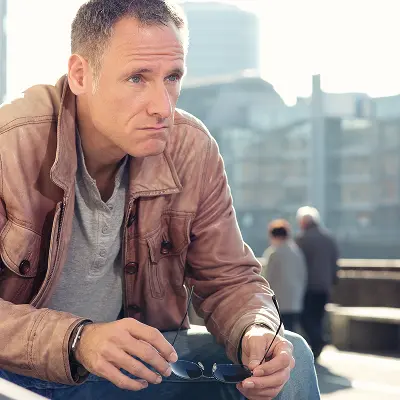 Mann Mitte 40 in Lederjacke blickt nachdenklich in die Ferne – Akademiker Coaching Berlin für berufliche Neuorientierung mit 45+