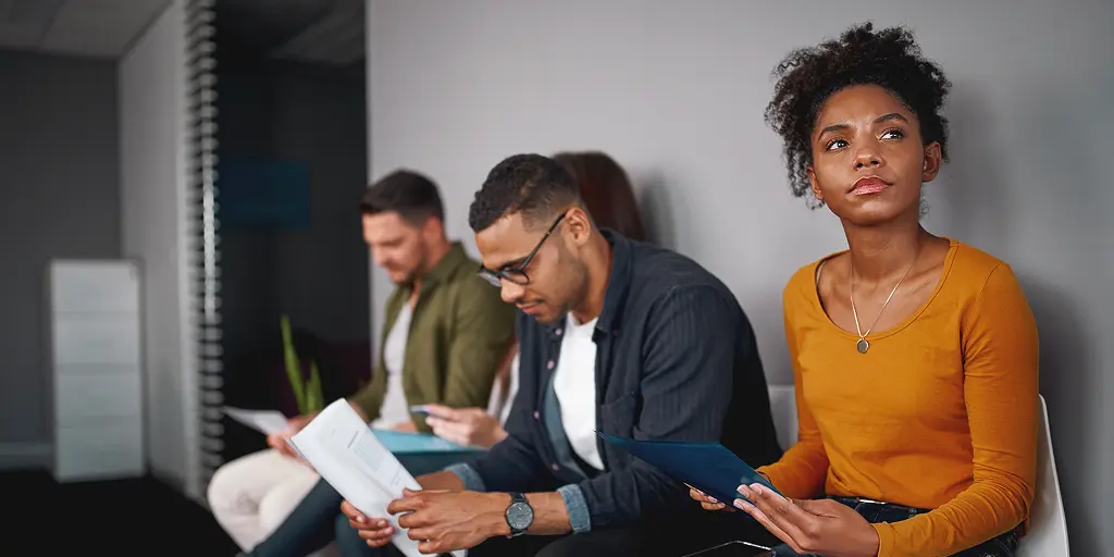 Bewerber:innen im Wartebereich vor dem Interview, bereiten sich auf häufige Fragen im Bewerbungsgespräch vor.
