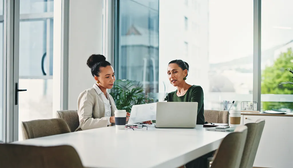 Bewerbungscoaching in Berlin: zwei Frauen im Gespräch an einem Tisch mit Laptop in heller Büroumgebung